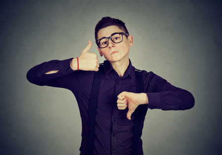 Perplexed young man with thumbs down thumbs up gesture