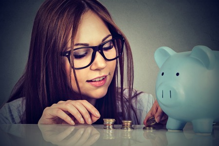Young woman counting money stacking up coinsの写真素材