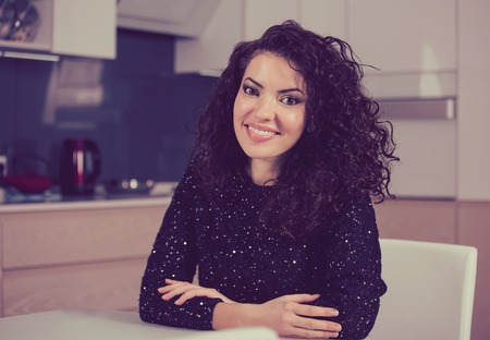 Happy woman smiling at camera while sitting at home in the kitchen
の写真素材