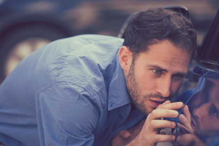 Young worried funny looking man obsessing about cleanliness of his new car. Car care and protection...