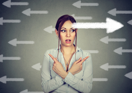 Young woman has a second thought choice perplexed pointing fingers in two different direction 