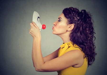 Woman kissing clown mask isolated on gray wall background の写真素材