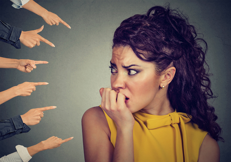 Anxious woman judged by different people fingers pointed at her. Concept of accusation of guilty girl. Negative human emotions face expression feeling  の写真素材