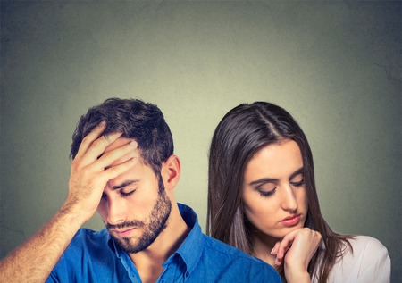 portrait stressed sad young couple man and woman looking down isolated on gray wall background の写真素材