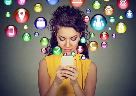 Happy young woman using texting on smartphone with social media application symbols icons flying out...