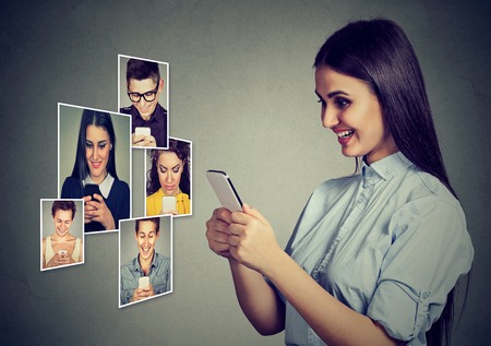 Stay connected. Happy young people men and women using mobile smart phone smiling.の写真素材