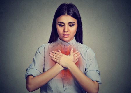 Young woman with asthma attack or respiratory problem isolated on gray backgroundの写真素材