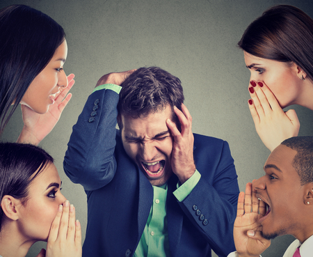 Group of people whispering to a desperate stressed business manの写真素材