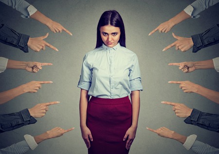 Concept of accusation of guilty person. Upset woman looking at camera many fingers pointing at her isolated on gray wall background. Human face expression emotion feelingの写真素材