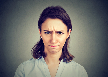Angry young woman isolated on gray background. Negative human emotions facial expression feelingsの写真素材