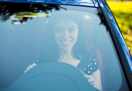 Windshield view of a young woman driving her new car.