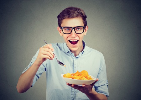 Young man having a plate of potato chipsの写真素材
