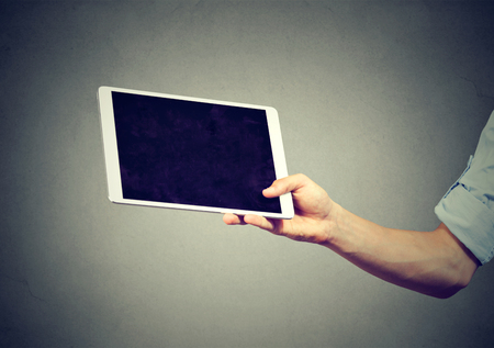 man hand holding tablet computer isolated on gray backgroundの写真素材