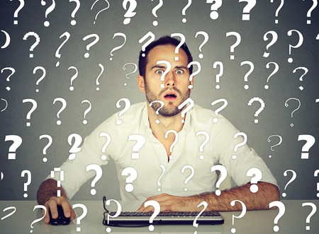 Amazed perplexed man working on desktop computer has many questions