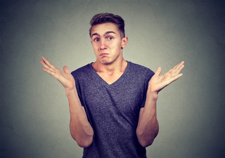 Closeup portrait young man shrugging shoulders isolated on gray wall background. Body languageの写真素材