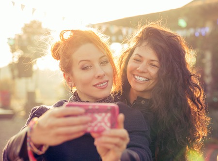 Female friends two women taking selfie having fun during weekend getaway Outdoorsの写真素材