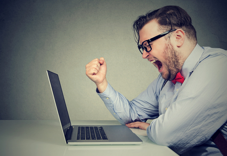 Side view of chubby young man in formal screaming in frustration while working with laptop. の写真素材