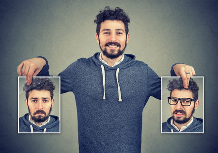 Young cheerful hipster holding photos with different emotions having problems with mood change. の写真素材