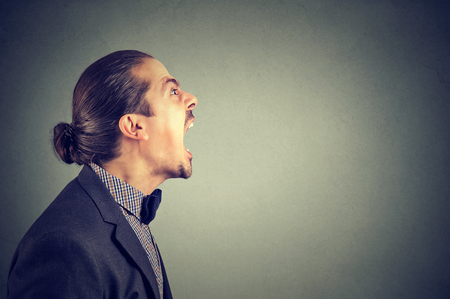 Side view of angry business man yelling in madness looking away. の写真素材