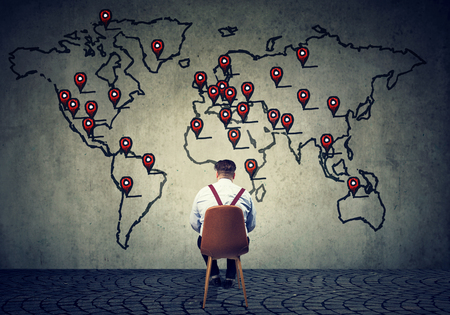 Concept shot of a business man on chair in front of map planning global corporation. の写真素材