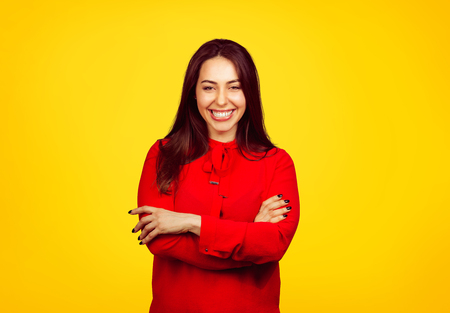 Young stylish brunette in red shirt smiling excitedly at camera on vibrant yellow background. の写真素材