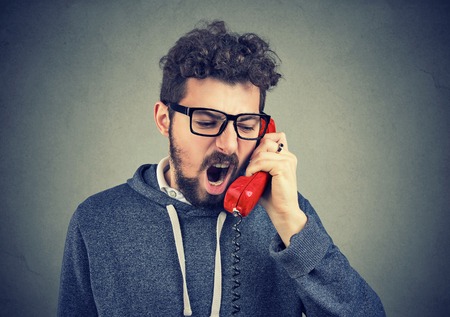 Young angry man yelling on the phoneの写真素材