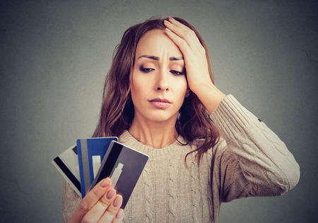 Young woman holding credit cards and looking stressed having financial problems. の写真素材