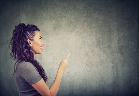 Side view of excited woman holding finger up having bright idea on gray backgroundの写真素材