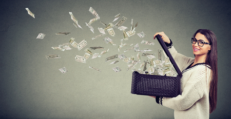 Excited successful super happy woman opening a box with money flying out away の写真素材