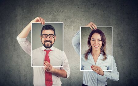 Happy young man and woman holding self portraitsの写真素材