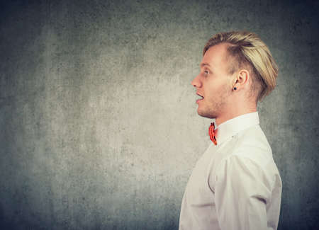 Side profile of a talking young man on grey wall backgroundの写真素材