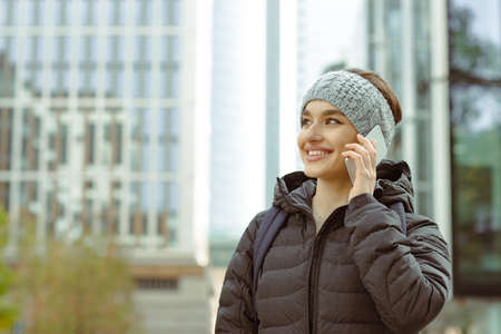 Portrait of a beautiful young woman talking on the cellphone walking in the cityの写真素材