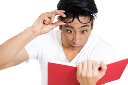 portrait of young man, with wide opened eyes staring at a book page, shocked, surprised by the twists and turn of story, isolated on white background.の写真素材