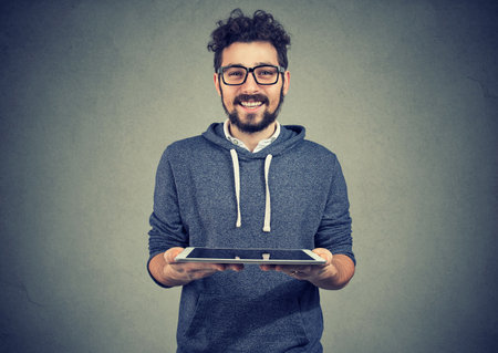 Cheerful man tech geek with tablet computer offering digital solutionsの写真素材
