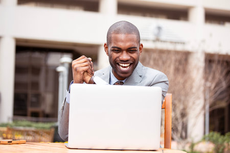 Thrilled business man reading great news on his laptop computer celebrates successの写真素材