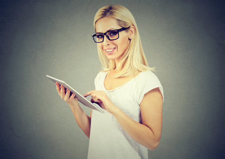 Happy woman in glasses, using tablet computerの写真素材