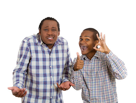 Closeup portrait two men, workers friends, one being arrogant, pessimistic, skeptical, clueless, rude, second showing OK sign, thumbs up, polite, optimistic isolated white background. Emotionの写真素材
