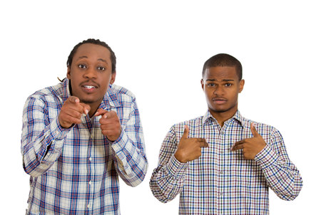 Closeup portrait two men, one pointing at himself, confused, denying mistakes, other serious, angry concerned pointing blaming someone isolated white background. Emotion contrast, reaction, perceptionの写真素材