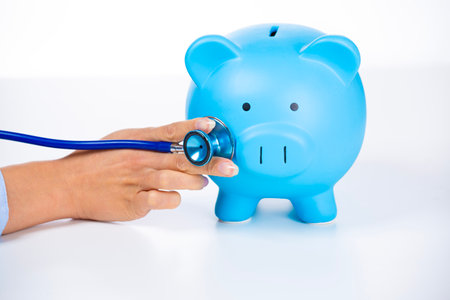 Business woman with stethoscope listening to piggy bankの写真素材