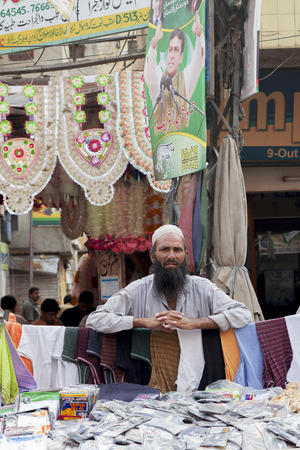 Lahore, Pakistan - April 26, 2013: Muslim street vendor with big black beard and white cap at selling clothes always busy Anarkali Bazaarのeditorial素材