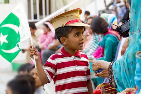 Lahore, Pakistan - May 5, 2013: Unidentified proud Pakistani kid with flag and military cap at a public celebration with his motherのeditorial素材