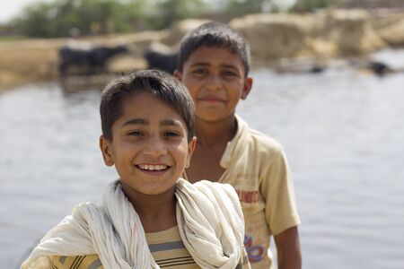 Lahore, Pakistan - May 9, 2013: Portrait of 2 pakistani boys playing by the river while shepherding cows in Lahore outskirtsのeditorial素材