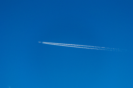 Bright blue sky with airplane trailの写真素材