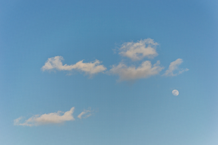 Bright blue sky with clouds and waning gibbous moonの写真素材