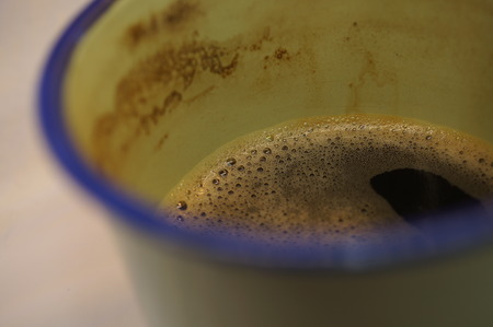 Macro close-up shot of nice coffee foam on the surface of a strong black coffee in a geen and blue cupの写真素材