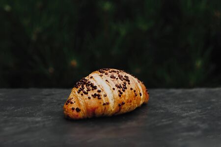 Fresh and tasty croissant with chocolate on black stony backgroundの写真素材