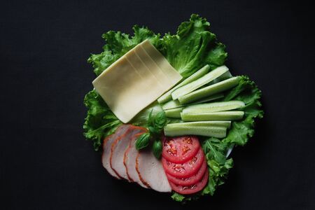 Food tray with delicious salami, pieces of sliced ham, cheese, tomatoes, salad and vegetableの写真素材
