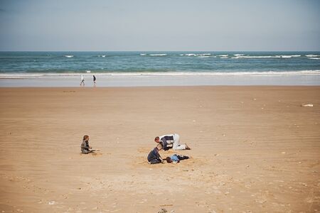 Tarfaya, Morocco - January 18, 2020: Father with sons have fun playing in the sand on the ocean coast, Africaのeditorial素材