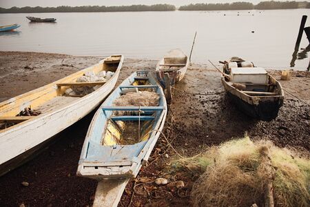 Picturesque view of old fishing boat on beach near river water on background at sunsetの写真素材