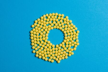 Yellow medical pills on blue background with copy space for text. Alternative homeopathy medicine, healthcare and wellness concept. Selective focusの写真素材
